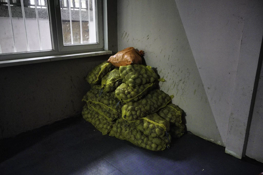 Stack of mesh potato sacks piled in a corner beneath a window
