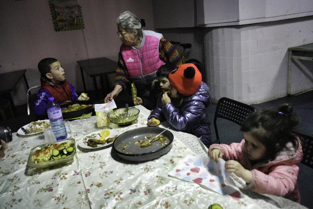 Elderly woman and children sharing a meal at a patterned table