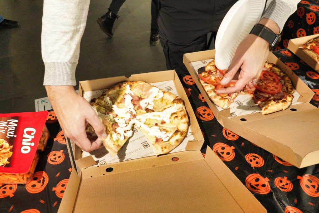 Hands reaching for Halloween pizza