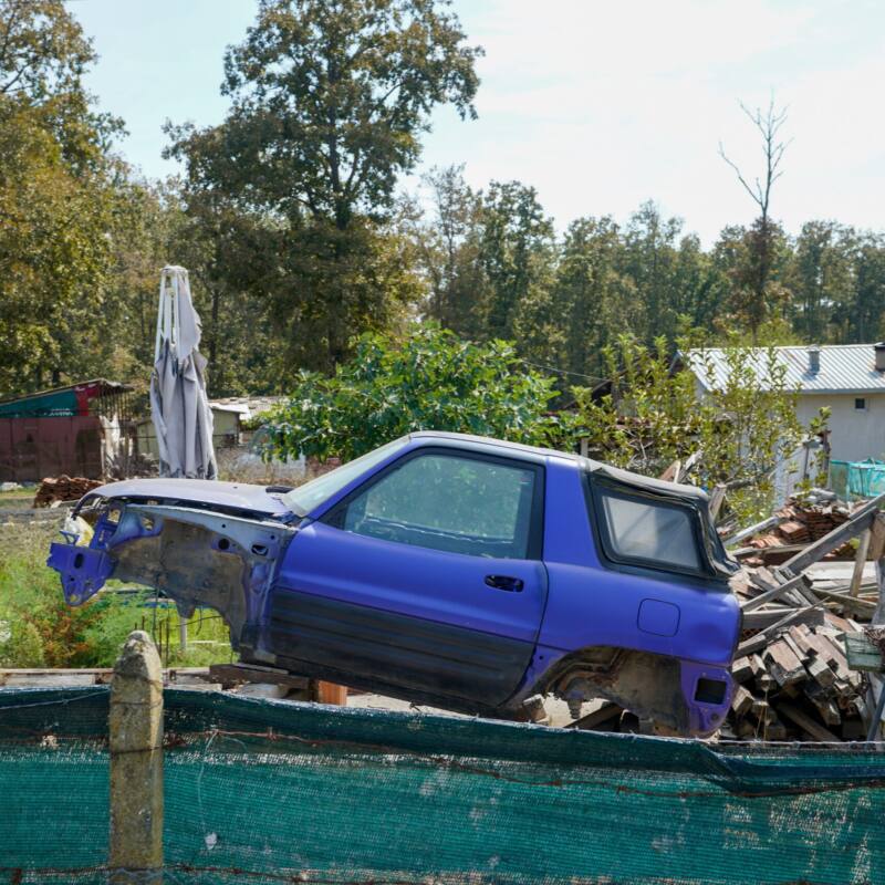 Stripped blue SUV in a rural yard, documentary photography