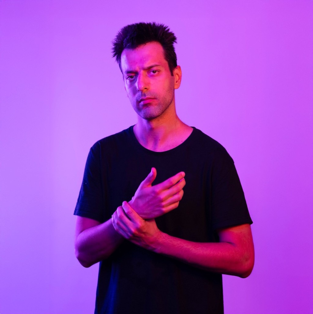 Portrait of Todor Stoyanov in a black t-shirt against a vibrant purple background with dramatic magenta lighting