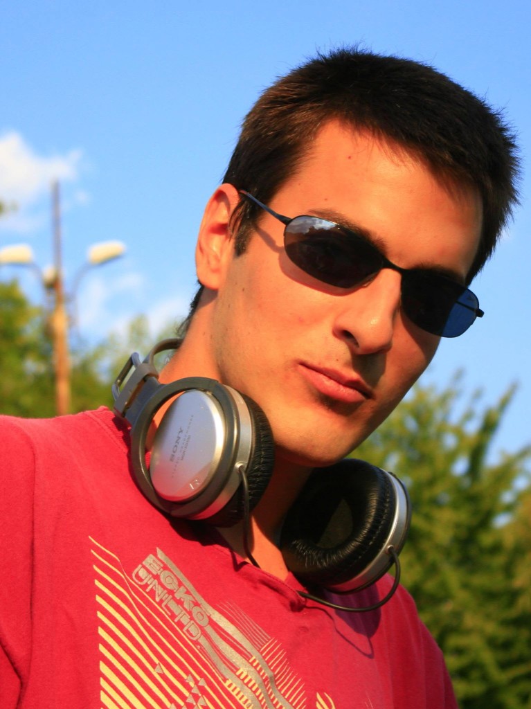 Portrait of Todor Stoyanov outdoors in a red shirt with sunglasses and Sony headphones around his neck
