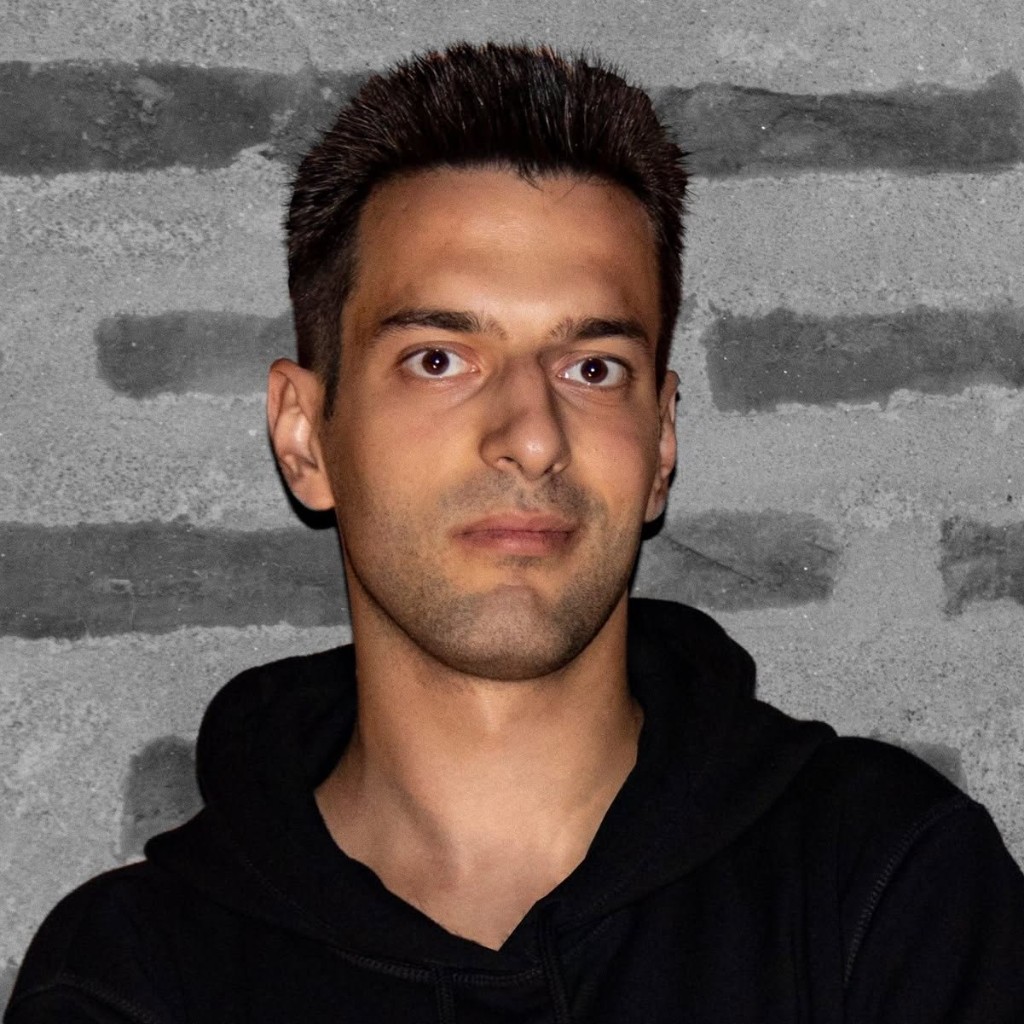 Headshot of Todor Stoyanov in a black hoodie against a grey brick wall